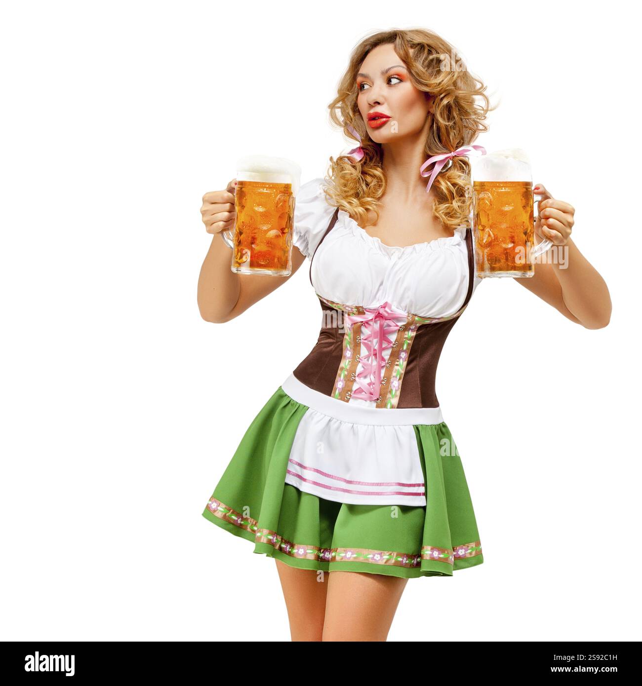 Foto creativa della cameriera dell'Oktoberfest che indossa un tradizionale costume bavarese con birra davanti a uno sfondo bianco Foto Stock
