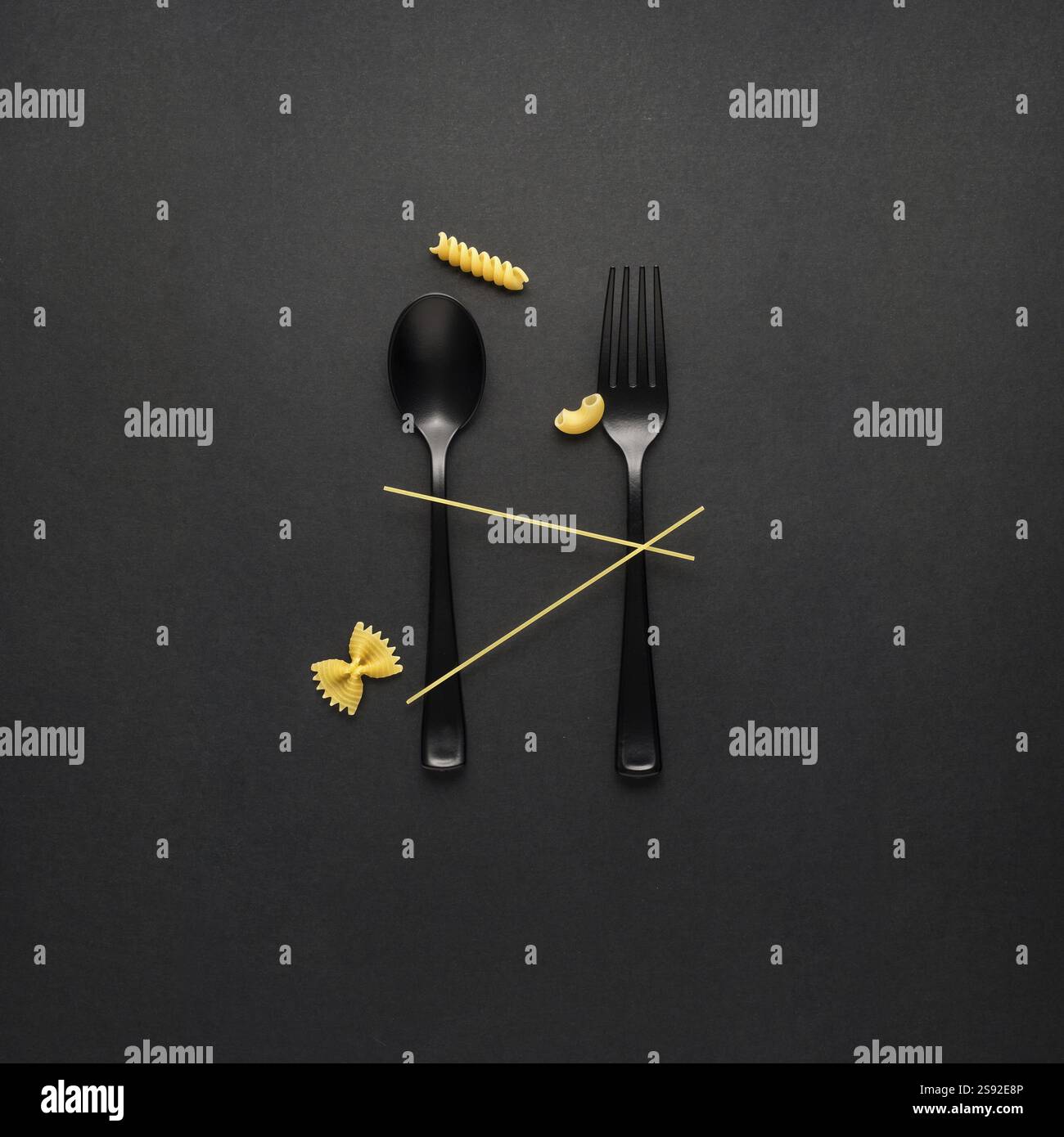 Foto creative di STILL Life con forchetta e cucchiaio con pasta cruda su sfondo nero Foto Stock