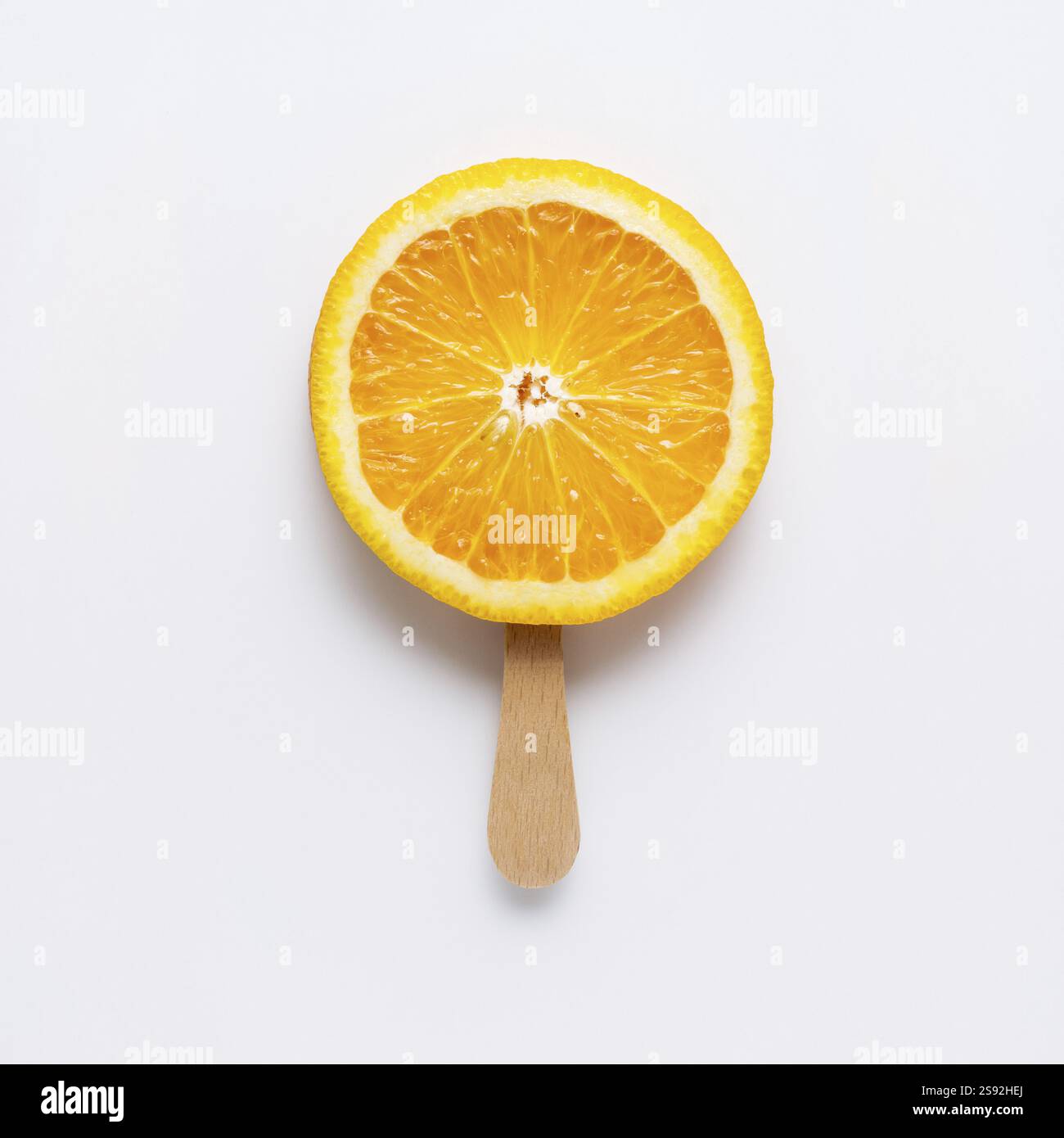 Foto creativa di una fetta arancione disposta come un popsicle su uno sfondo grigio Foto Stock