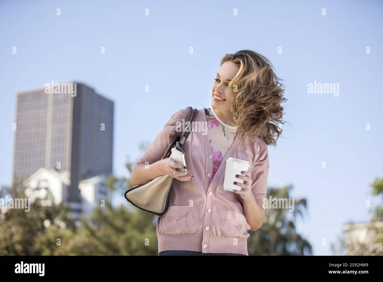 Una bella donna che controlla le e-mail sul suo cellulare in un parco cittadino Foto Stock
