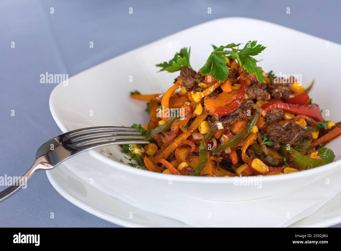 Strisce sfrigolanti di manzo con peperoni rossi e fajitas di peperoni verdi con prezzemolo, manzo di Pechino, mais e cibo di strada Foto Stock
