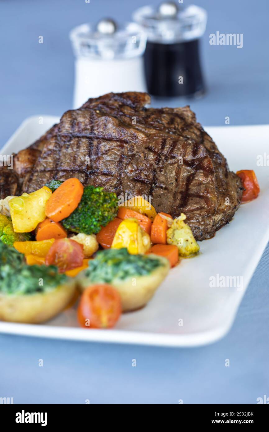 bistecca grigliata di manzo sfrigolante con verdure, carote, patate, broccoli, zucchine e spinaci panna Foto Stock