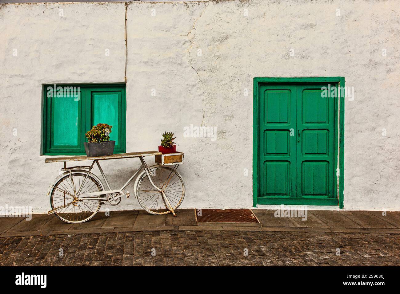 Biciclette parcheggiate fuori dalla tipica dimora di Lanzarote con porte e finestre verdi. Foto Stock