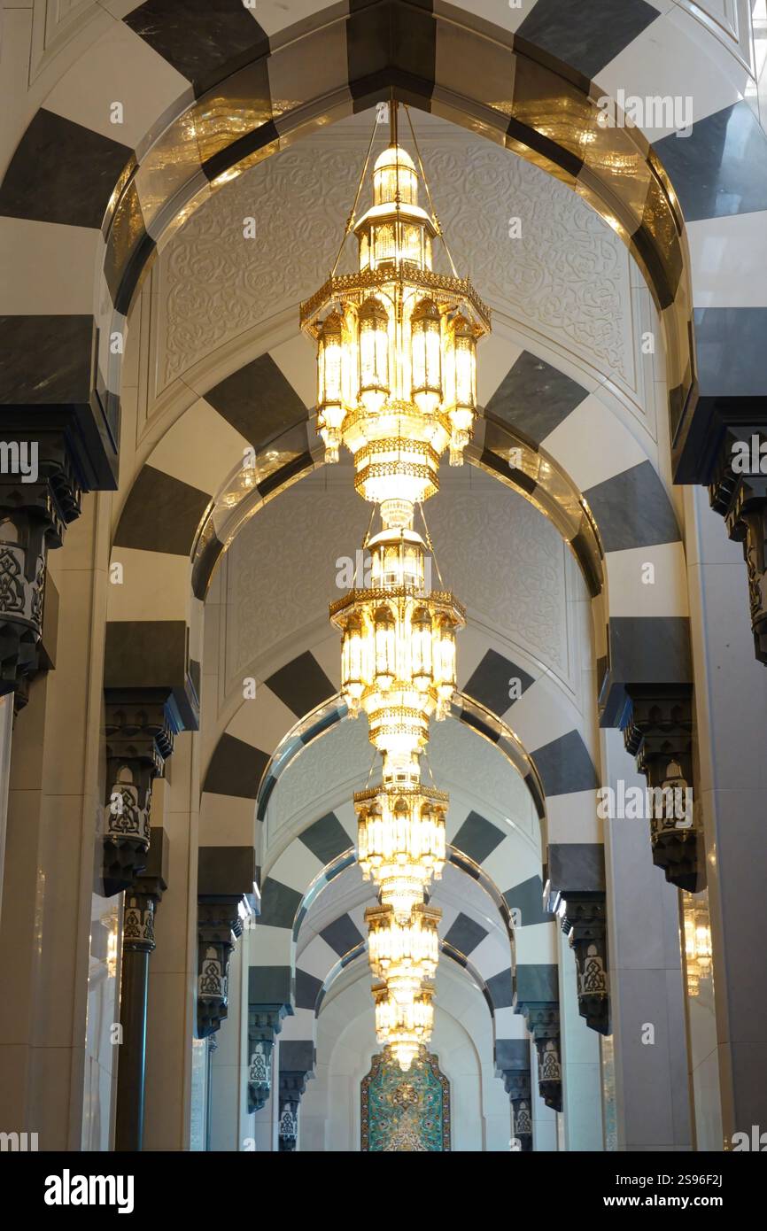 Portici in marmo bianco e grigio con diversi lampadari al centro della grande Moschea del Sultano Qaboos. Foto Stock