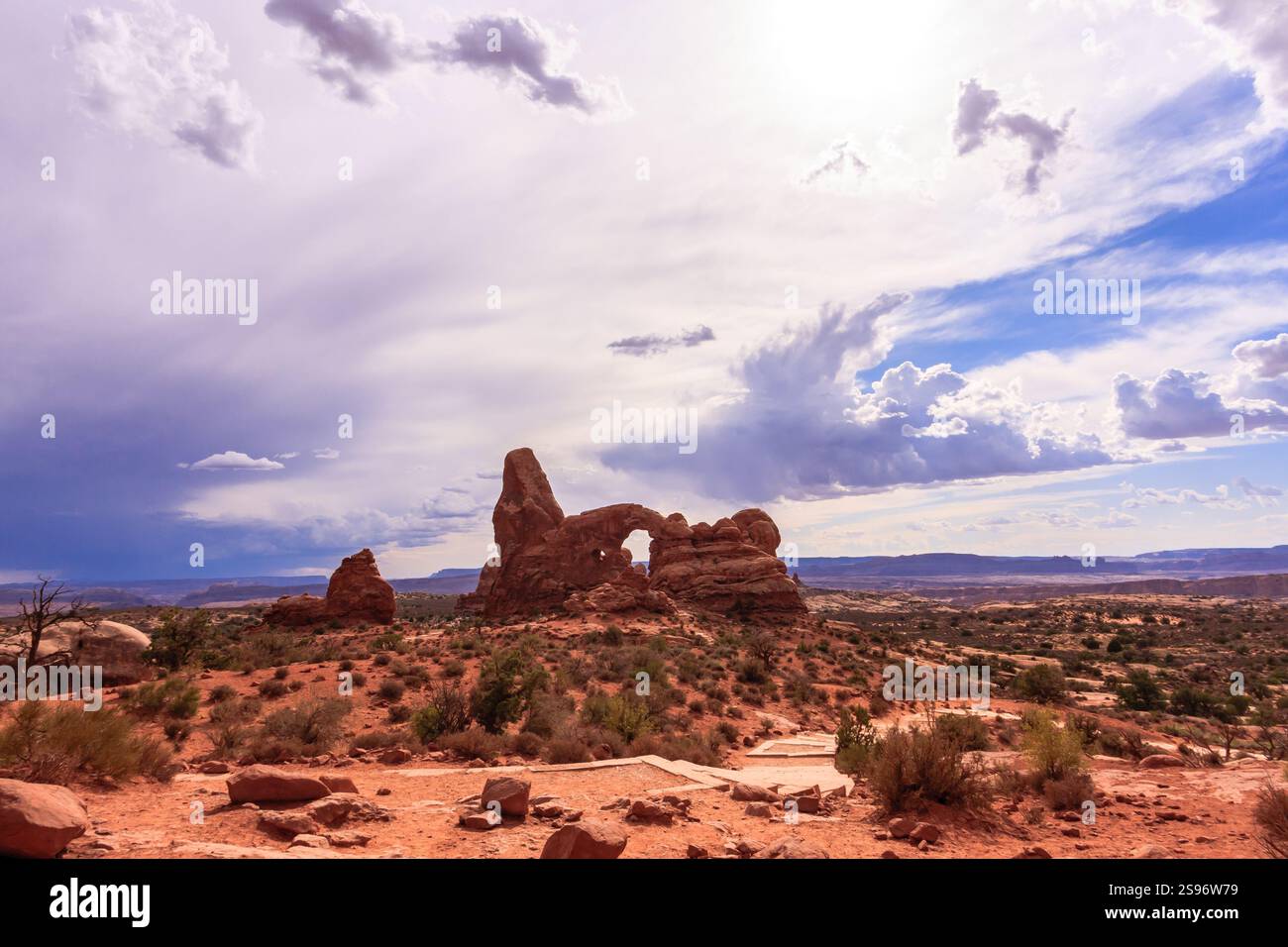 Un paesaggio desertico con una grande formazione rocciosa e un cielo senza nuvole. Il cielo è blu e il sole splende Foto Stock