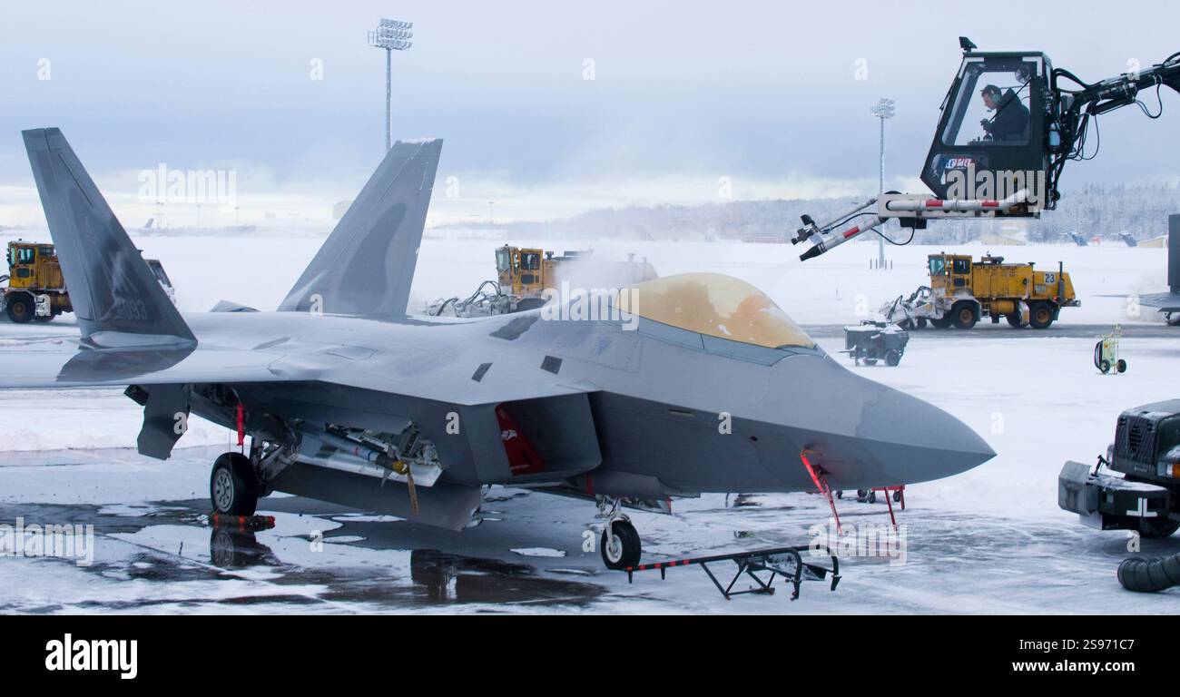 BASE AEREA DI ELMENDORF, Alaska - Senior Airman Alexander Buck, 3rd Aircraft Maintenance Squadron, de-ices un F-22A mentre 3rd Civil Engineer Squadron Foto Stock