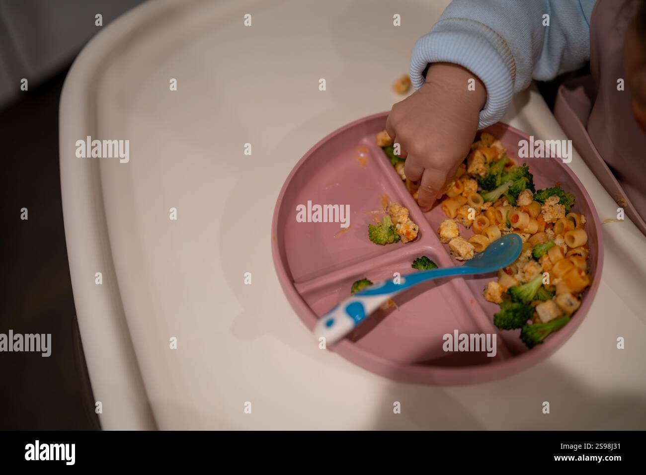 Il bambino mangia pasta e broccoli Foto Stock
