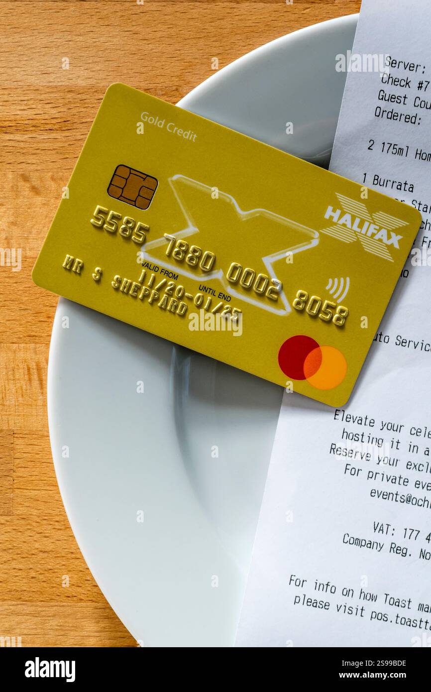 Carta di credito con conto su un piattino per pagare un pasto in un ristorante. Foto Stock