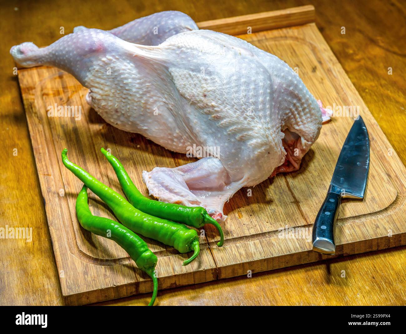 Preparazione di tacchino crudo su tagliere di legno con verdure e coltello Foto Stock