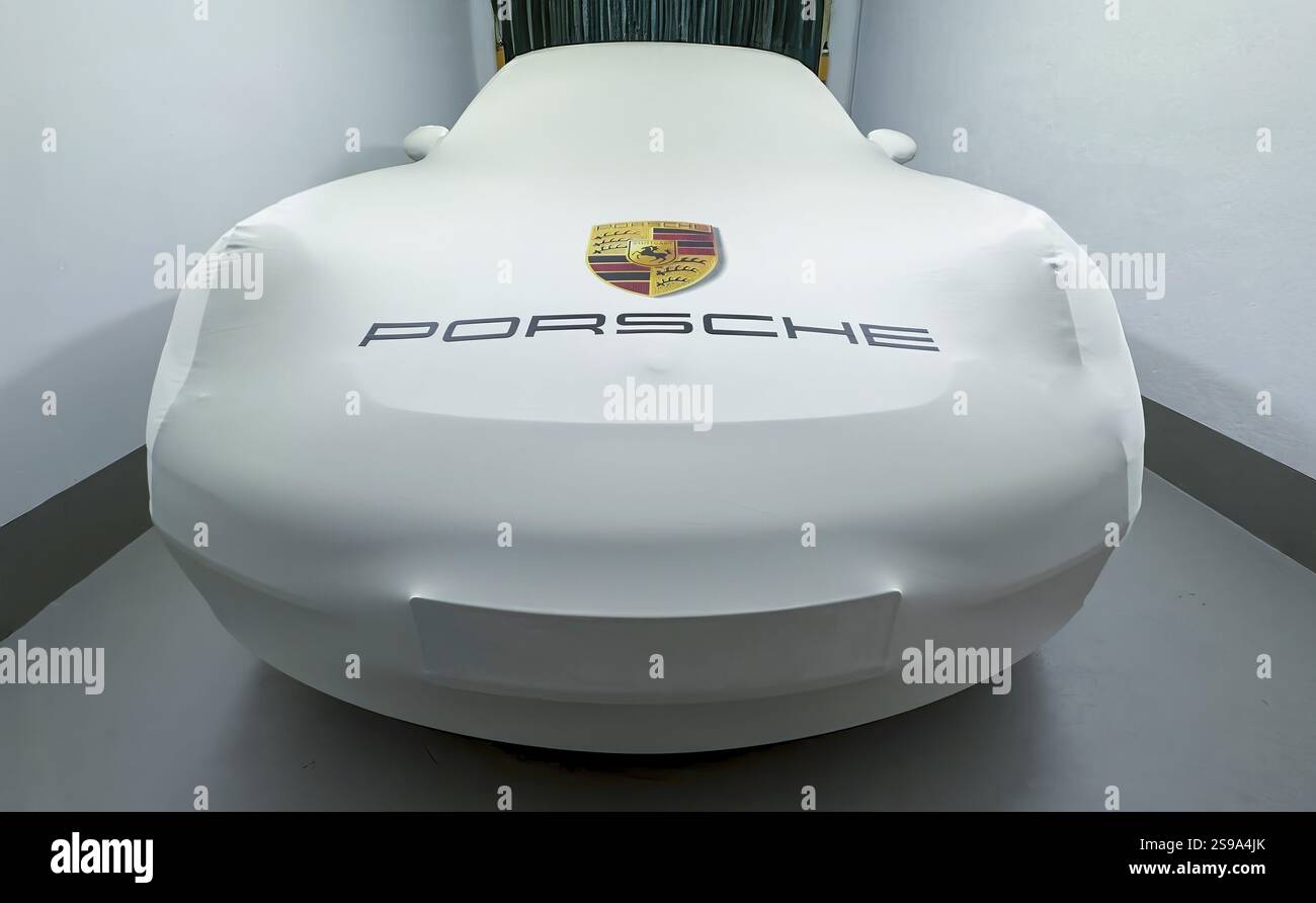 L'auto sportiva Porsche 911 si trova in garage sotto la copertura protettiva con logo e scritta, internazionale Foto Stock