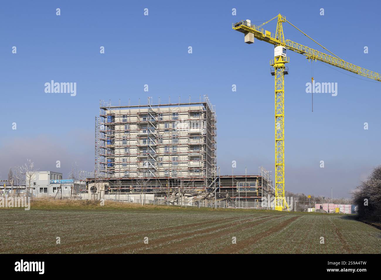 Edificio incompiuto con gru gialla, cantiere sotto il cielo blu, costruzione di abitazioni, nuova costruzione di 50 appartamenti, nuovo sviluppo Foto Stock