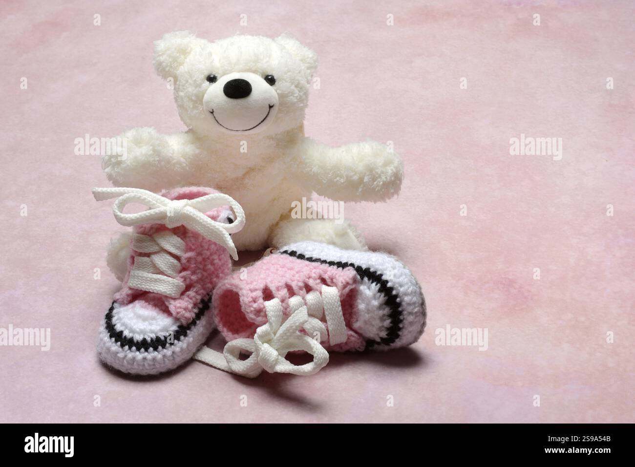 Scarpe per bambini rosa con orsacchiotto, sfondo rosa Foto Stock