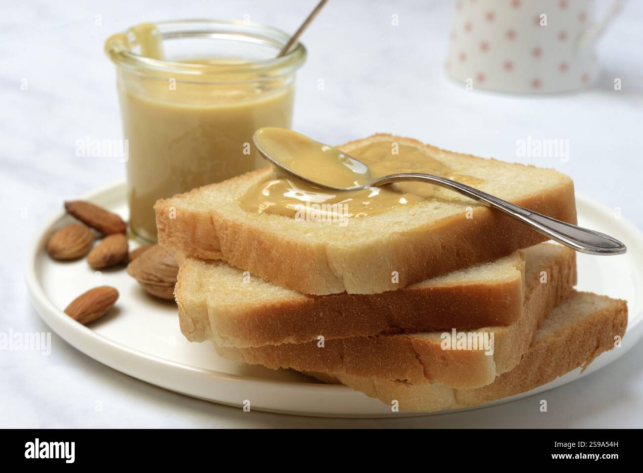 Panna di mandorle su pane tostato, mandorle e cucchiaio Foto Stock