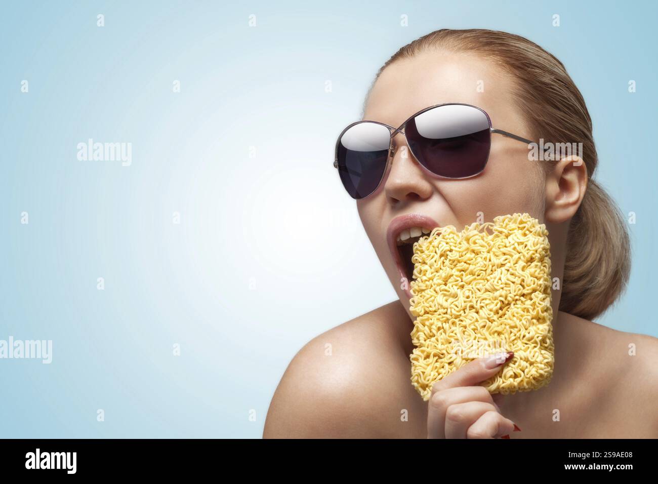 Una foto di una bella ragazza che morde in un bar di spaghetti a cottura veloce Foto Stock