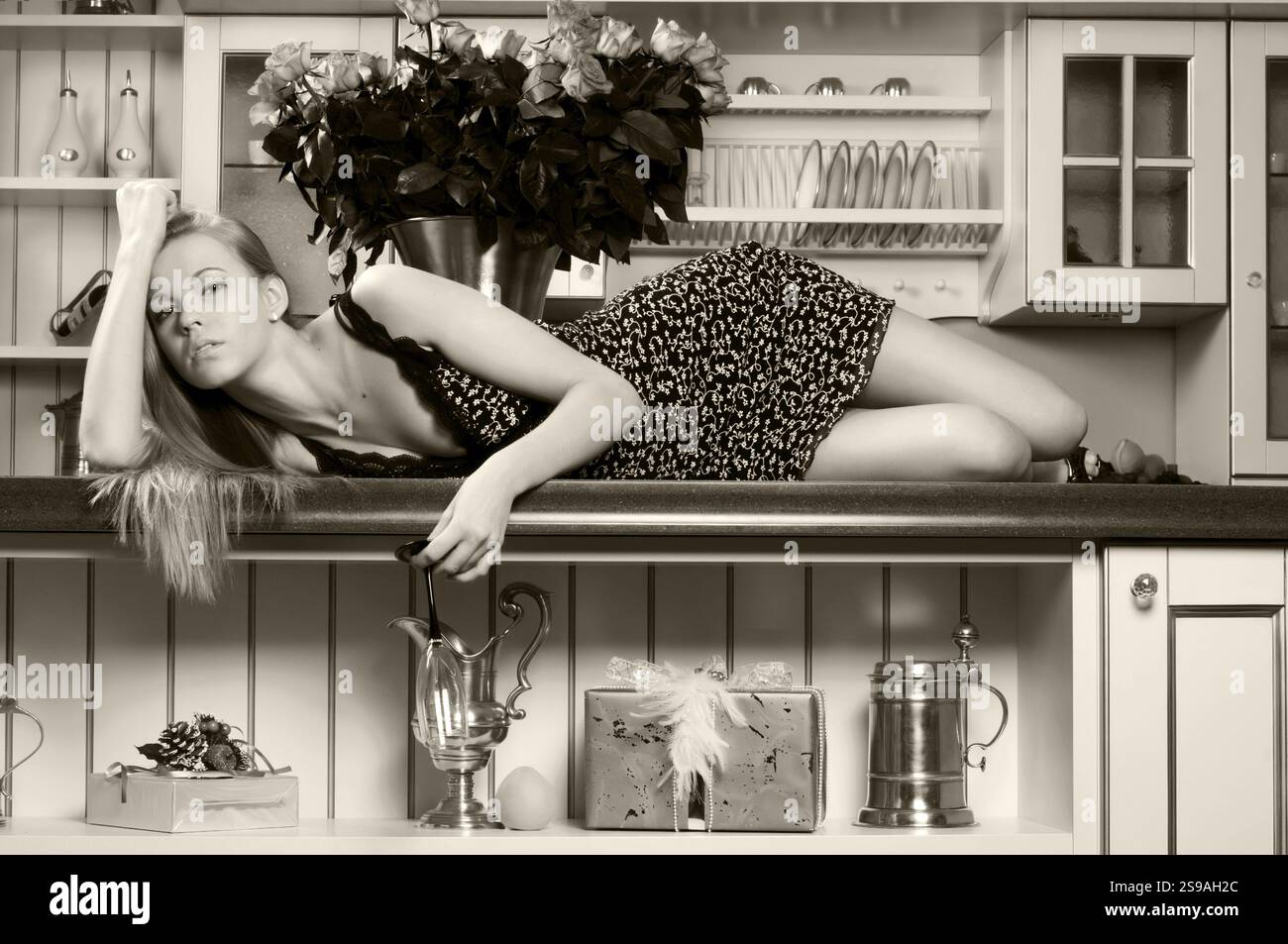 Ritratto della bella bionda. È sdraiata sul tavolo della cucina. Immagine monocromatica, ST. Pietroburgo, Russia, Europa Foto Stock