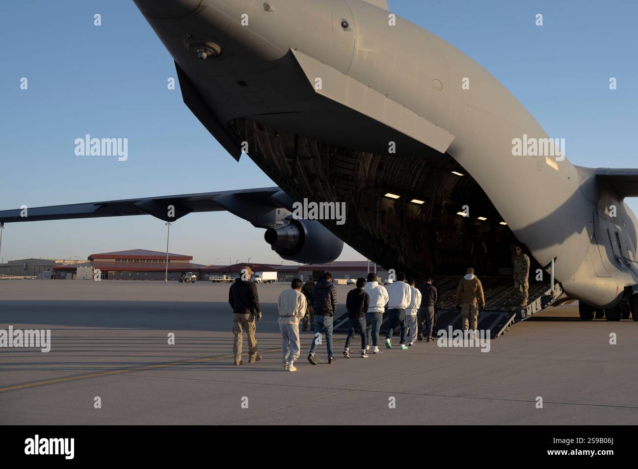 El Paso, Stati Uniti. 23 gennaio 2025. Gli agenti delle dogane e della protezione delle frontiere degli Stati Uniti guidano i migranti non documentati verso una U. C-17 Globemaster III della S Air Force trasportava aerei per il primo volo di rimozione in Guatemala da Fort Bliss, 23 gennaio 2025 a El Paso, Texas. I voli di rimozione erano diretti dal presidente Donald Trump ed è la prima volta che gli aerei militari sono stati utilizzati per i voli di deportazione. Crediti: Sergente 1C Nicholas De la pena/U. S Army Photo/Alamy Live News Foto Stock