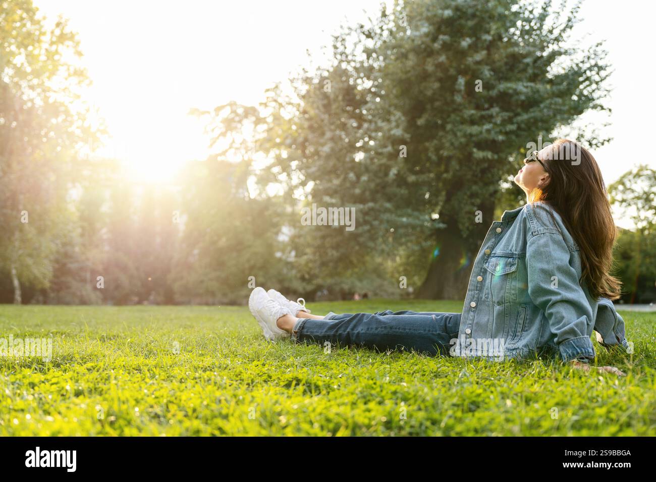 Donna urbana che riposa nel parco cittadino dopo il lavoro. Donna seduta su erba verde nel parco pubblico e rilassante. Foto Stock