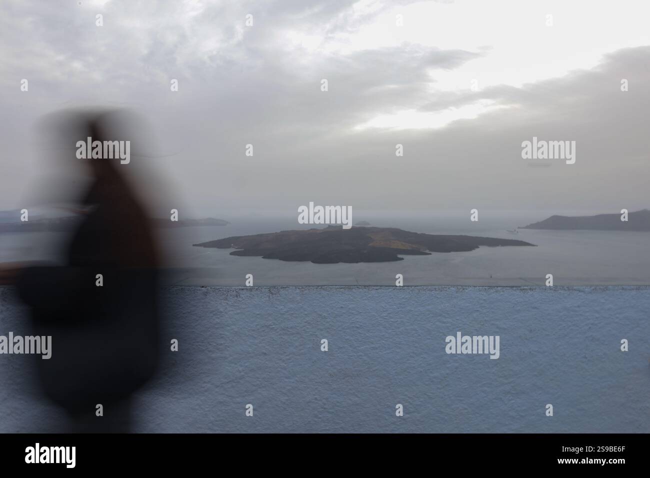 Vista del vulcano di Santorini al crepuscolo con un passante in movimento sfocato. Foto Stock