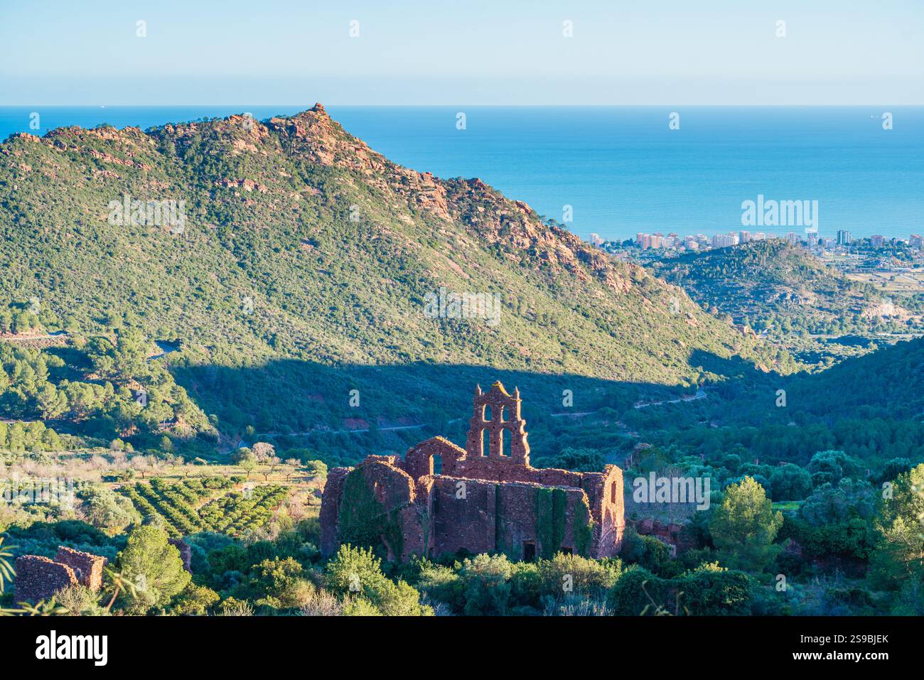 Vista panoramica del Parco naturale Desert de les Palmes nella provincia di Castellon, in Spagna, con le rovine di un monastero e il blu del Mar Mediterraneo sullo sfondo Foto Stock