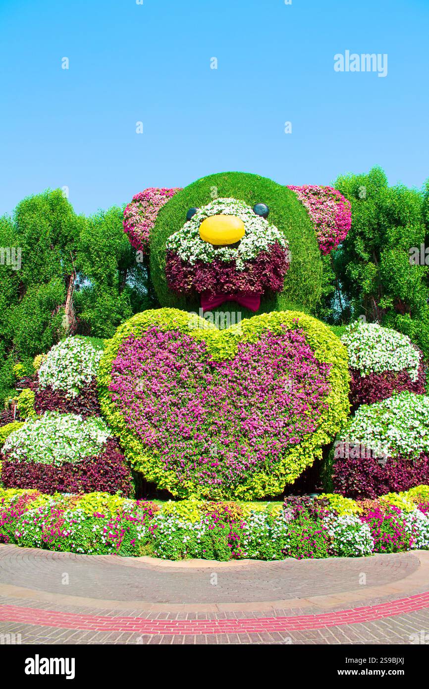 Orso con cuore fatto di cespugli di verde e fiori. Petunie. Giardinaggio, giardino con design floreale che indica l'attrazione turistica naturale sulla sunn Foto Stock