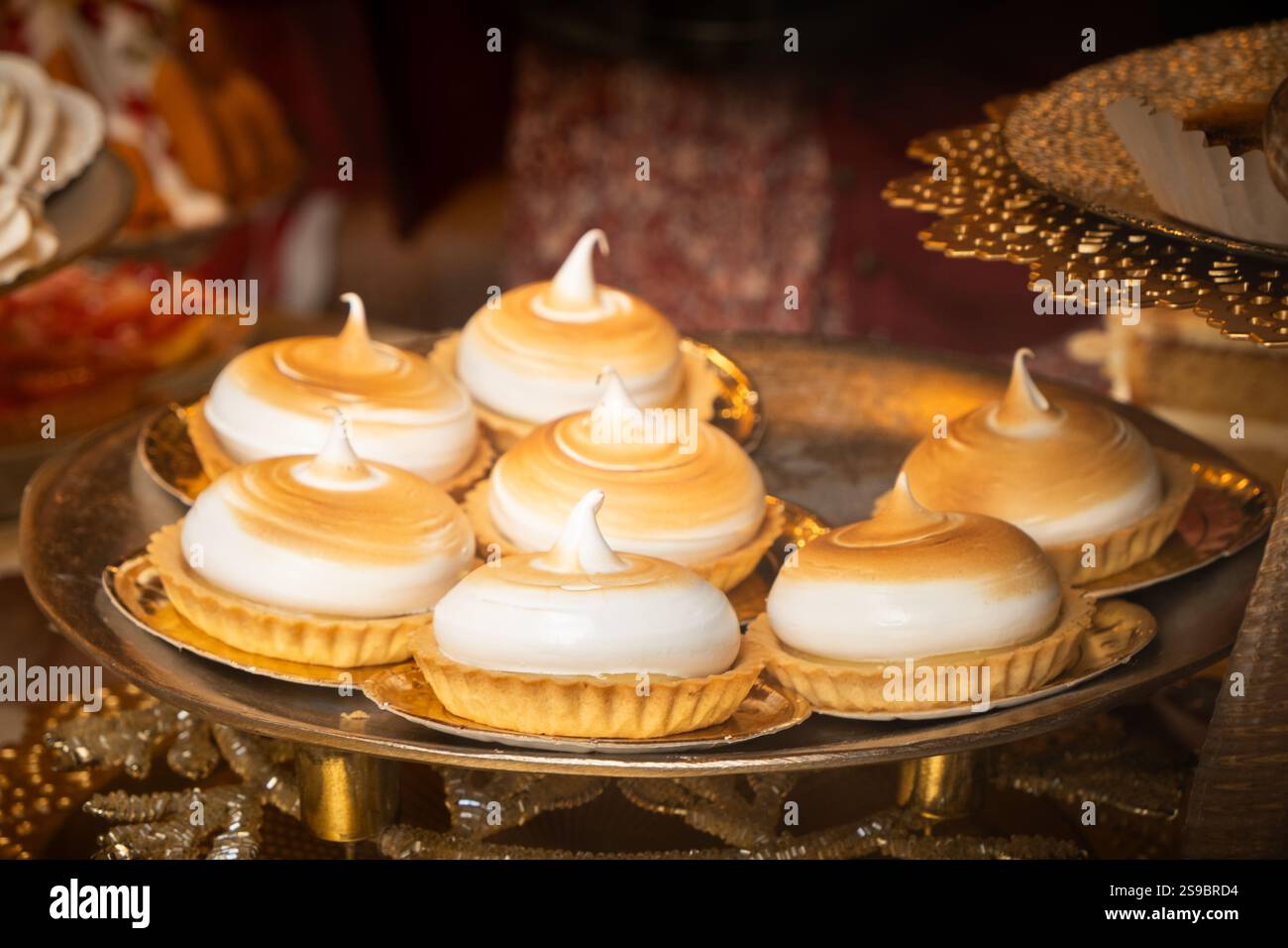 Un vassoio per torte a base di meringa e biscotti in una vetrina di una piccola azienda. Sono dolci e illuminate dal sole del pomeriggio. concetto di capriccio, dolce Foto Stock