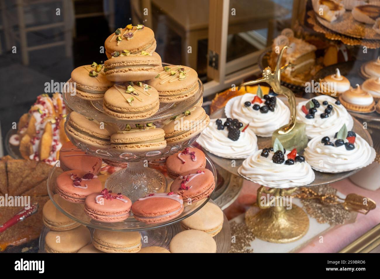 Dettaglio di una vetrina con diversi dolci e capricci di pasticceria. Ci sono macarron francesi di diversi sapori, torte e meringhe di frutta. I vassoi giv Foto Stock
