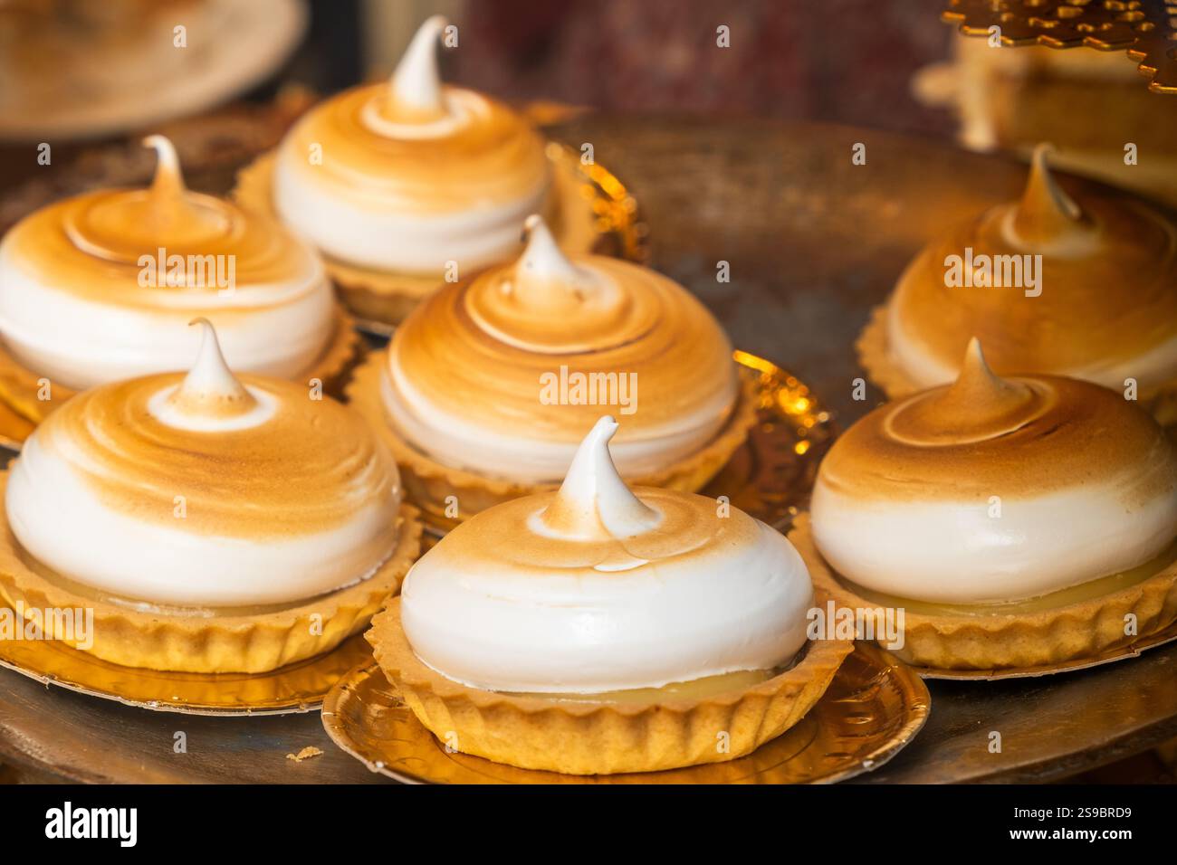 immagine dettagliata di un vassoio per torte fatto di meringa e biscotti in una vetrina di una piccola azienda. Sono dolci e illuminate dal sole del pomeriggio. concetto Foto Stock