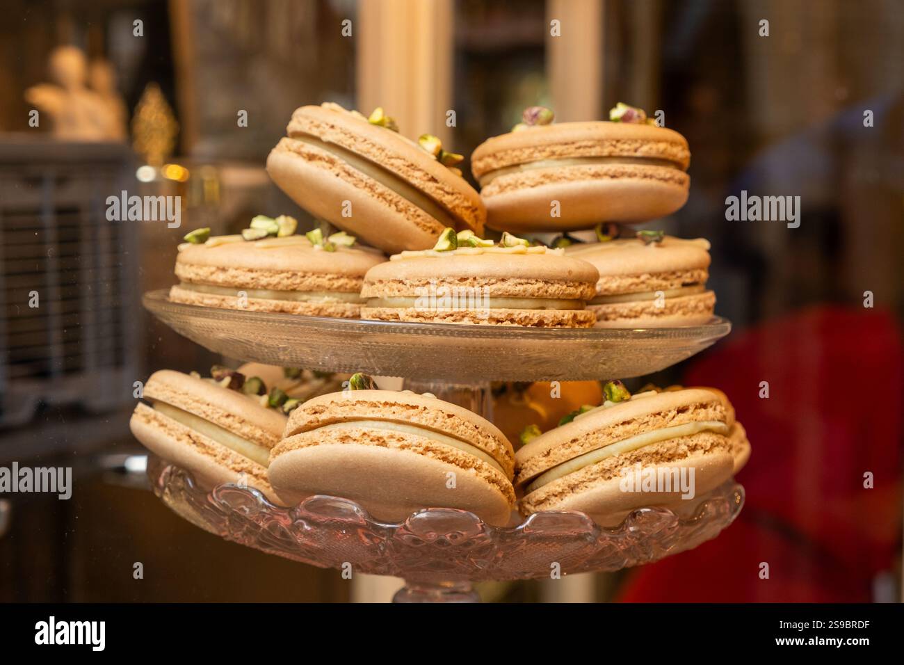Dettaglio di una vetrina di un piccolo panificio e di un'azienda dolce. C'è un vassoio di vetro a due piani ripieno di delizioso caffè francese al gusto di macarron. Il Foto Stock