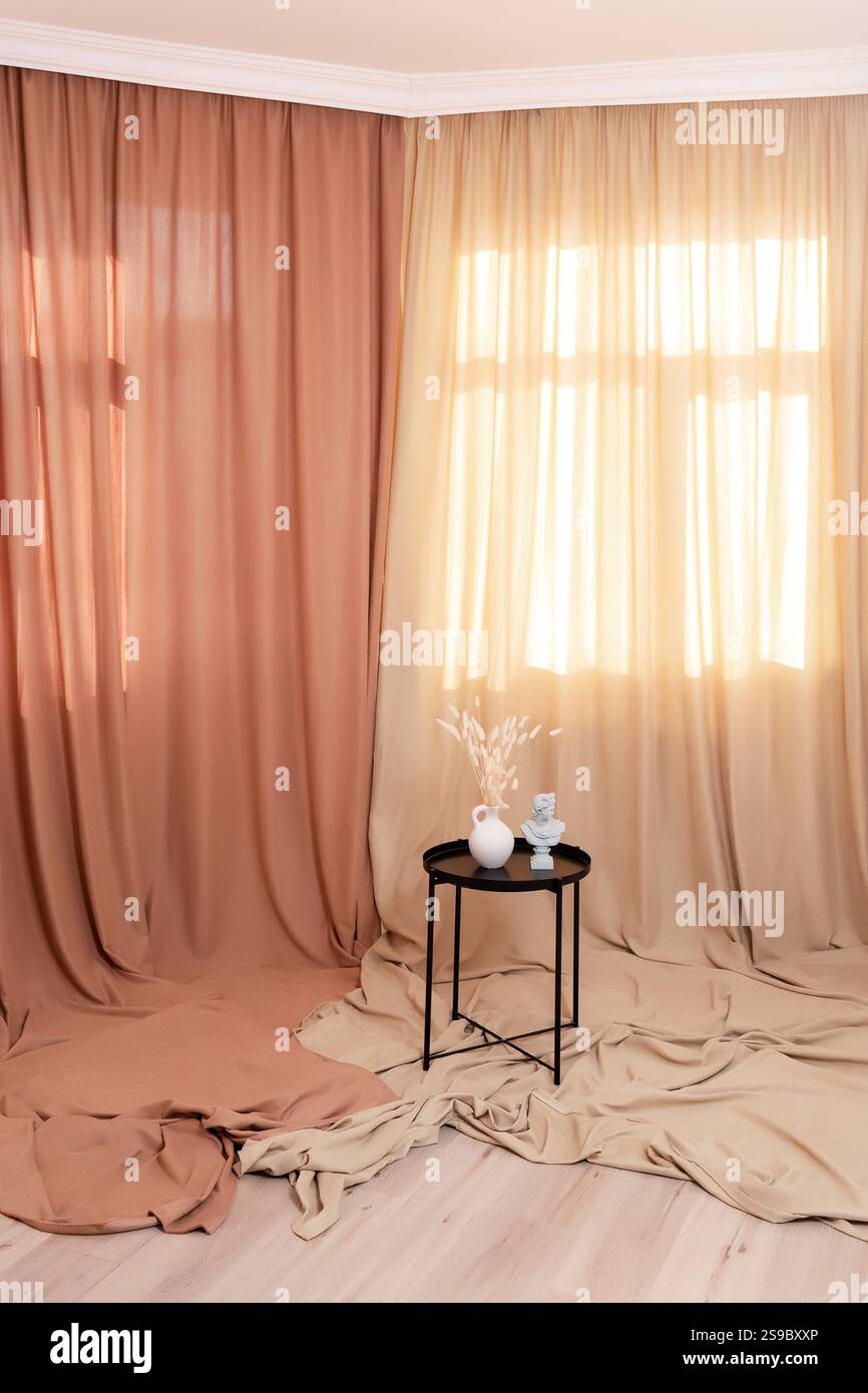 tavolo in metallo nero con vaso sullo sfondo di tessuto colorato. zona fotografica con tessuto di cotone Foto Stock