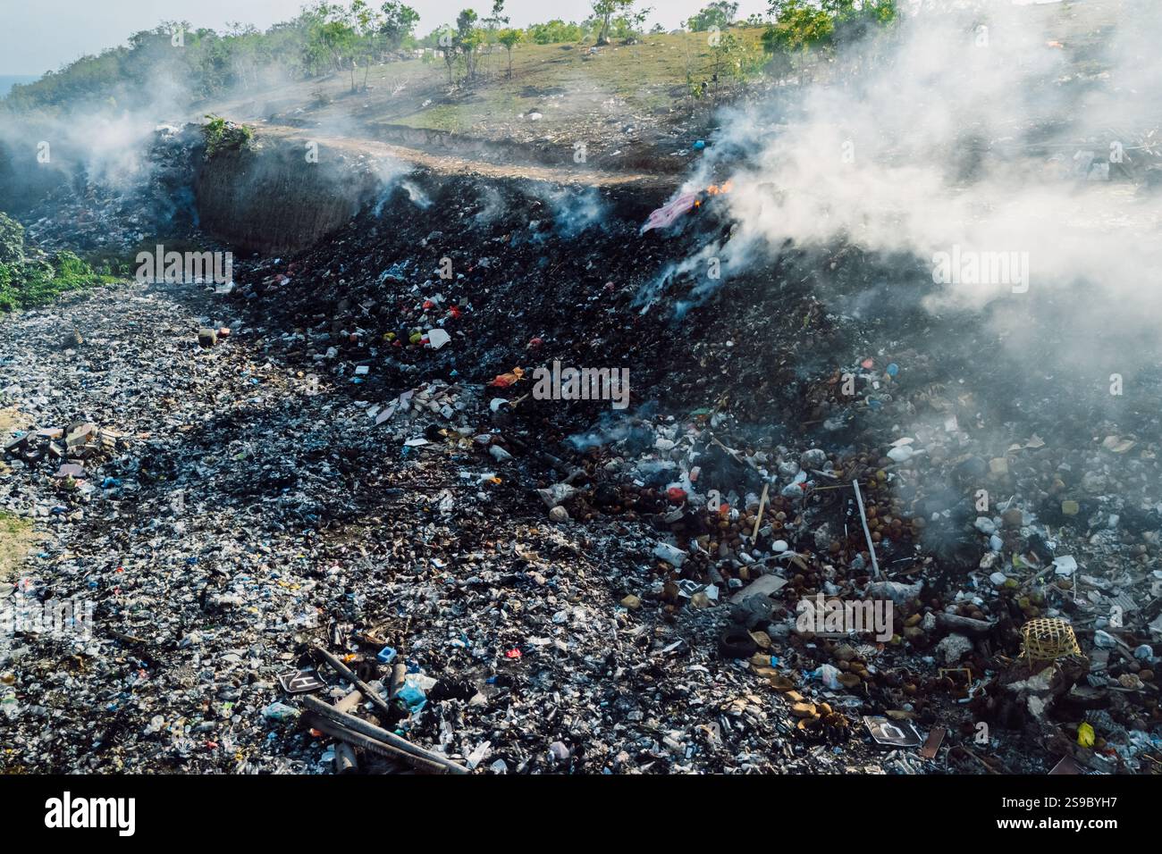 Bruciare le discariche che emettono fumo, evidenziando le sfide legate all'inquinamento ambientale e alla gestione dei rifiuti a Bali Foto Stock