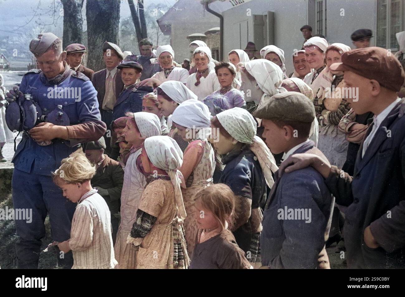 La popolazione locale a guardare i soldati tedeschi di acqua di riempimento di bottiglie in Iugoslavia nell'aprile 1941 durante il WW2 invasione tedesca della Jugoslavia. Questa immagine è stata presa da un ufficiale dell'esercito tedesco/soldier tra 14 - 18/4/1941 in Iugoslavia. Foto Stock