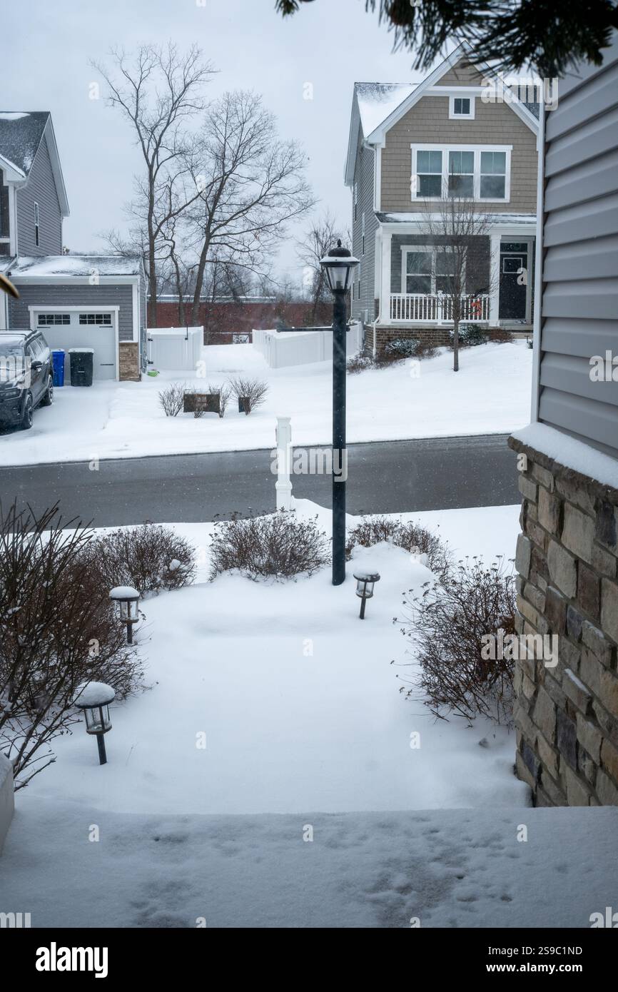 Un fresco strato di neve copre un'area residenziale, con case e lampioni che creano una tranquilla scena invernale in una mattinata grigia. Foto Stock