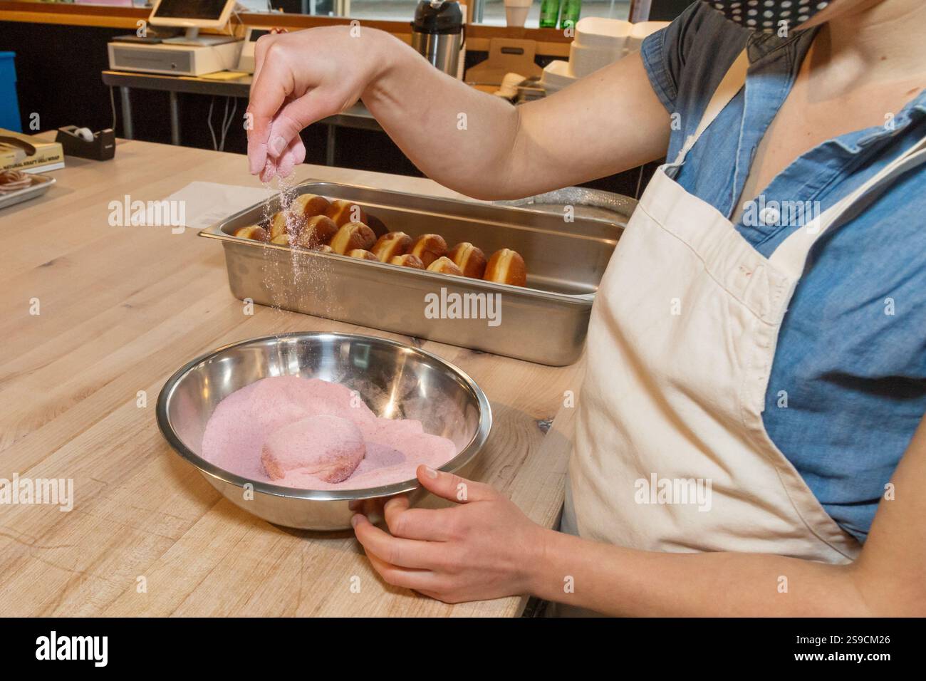 Ciambella ricoperta a mano in zucchero rosa in una ciotola di miscelazione in acciaio Foto Stock