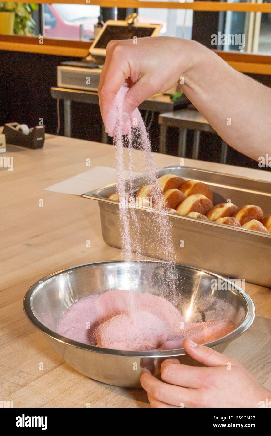 Ciambella ricoperta a mano in zucchero rosa in una ciotola di miscelazione in acciaio Foto Stock