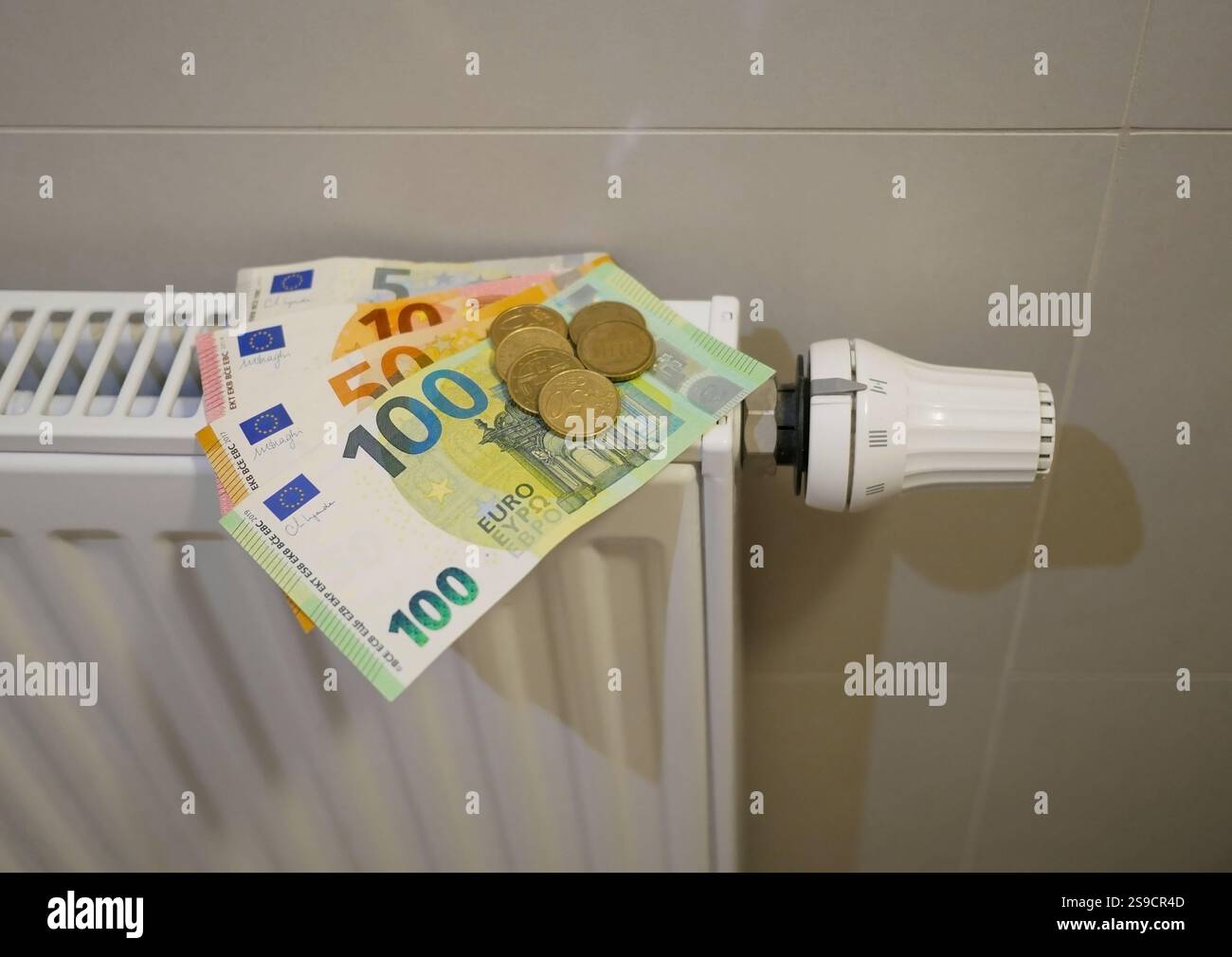 Soldi sulla batteria del radiatore di riscaldamento. Banconote in euro su manopola del termostato. Il concetto di aumentare i prezzi del gas e del riscaldamento, il prezzo delle bollette caro Foto Stock