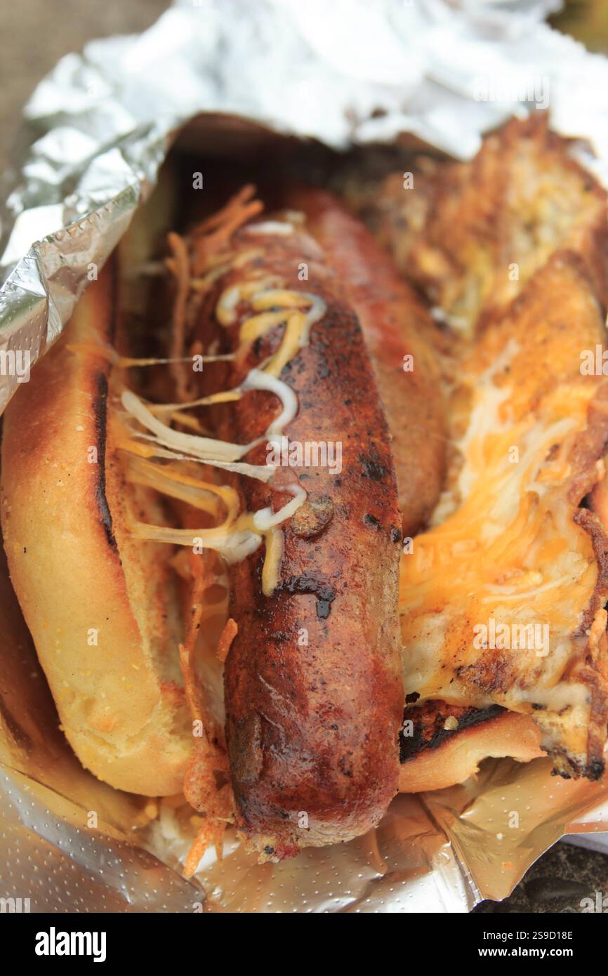 Sandwich di salsiccia alla griglia con formaggio fuso in foglio di alluminio Foto Stock