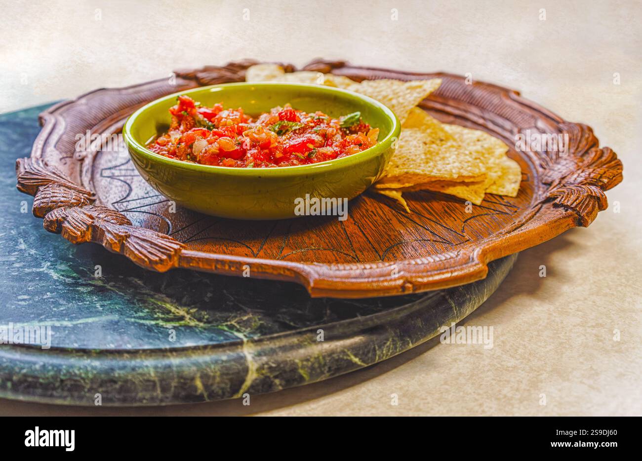 Salsa biologica fresca in una ciotola vintage e patatine di mais su un piatto di legno antico su un vassoio di marmo Foto Stock