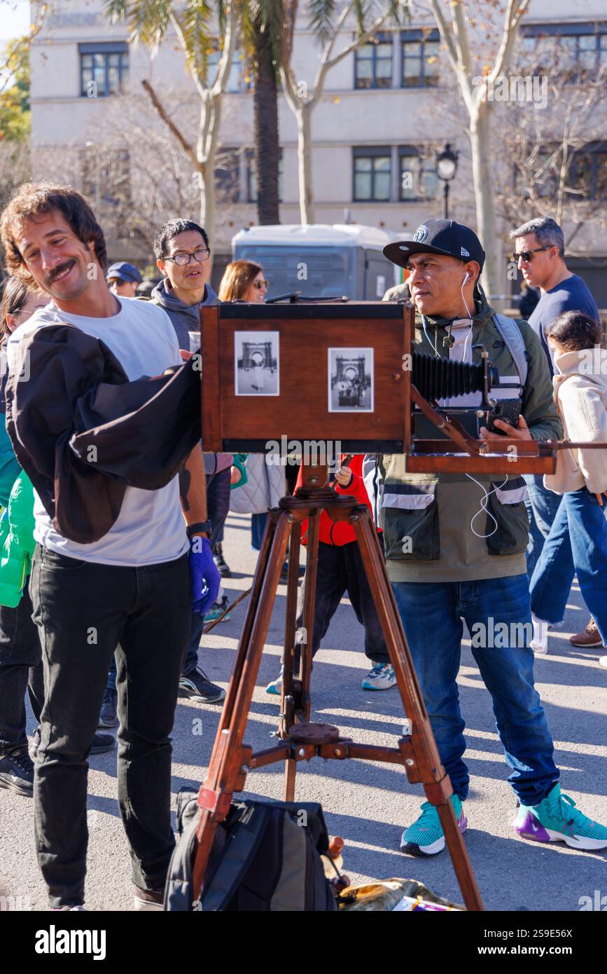 Barcellona - Spagna, 25 gennaio 2025: Un esperto fotografo d'epoca con una fotocamera anni '1900 fotografa il colorato Capodanno cinese. Foto Stock