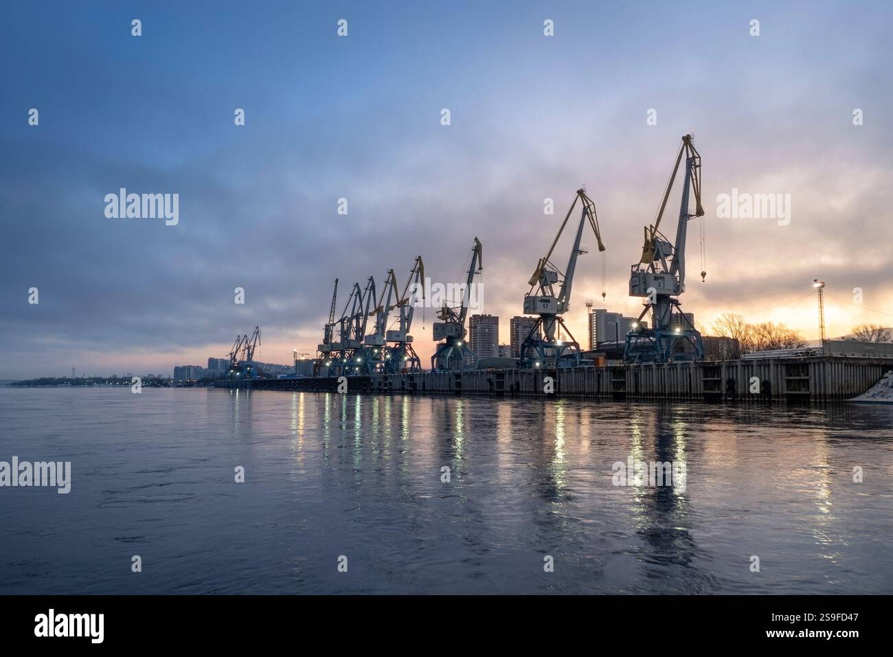 Un bellissimo porto marittimo industriale o un porto fluviale all'alba con gru e acque calme. Trasporto merci, spedizioni e logistica. Foto Stock