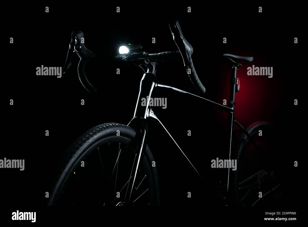 Bicicletta in ghiaia nera con illuminazione, faro bianco e lampeggiatore posteriore rosso, sicurezza in bicicletta su sfondo scuro. Foto Stock