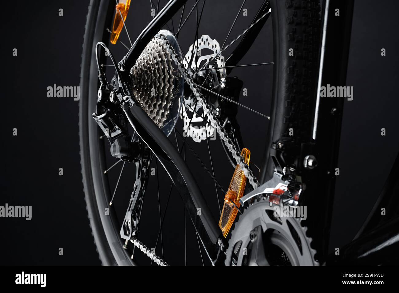 Primo piano della ruota posteriore della bicicletta con un intricato meccanismo di cambio marcia - leva del cambio, cassetta del pignone e catena su uno sfondo nero scuro. Foto Stock