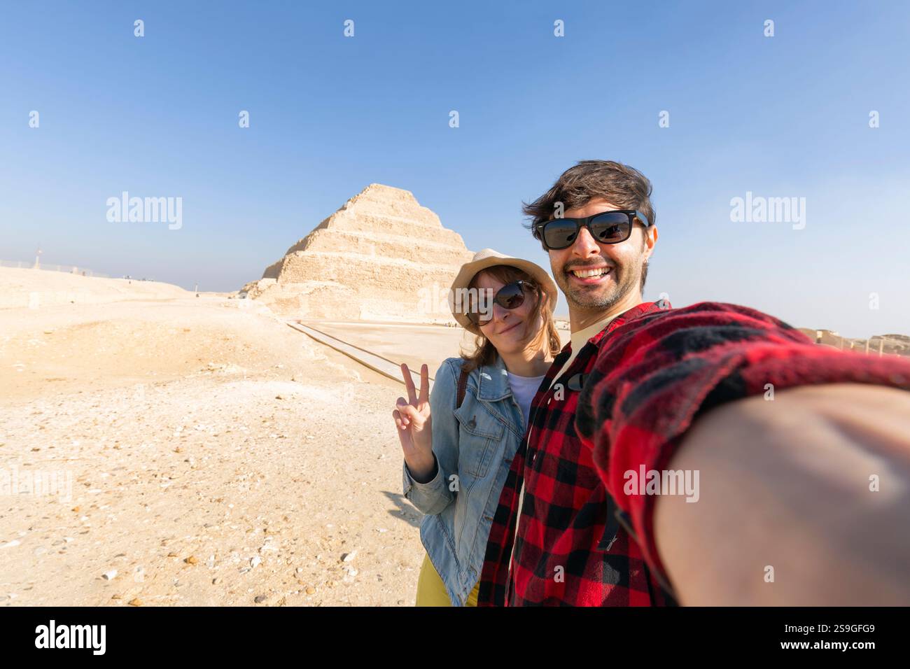 Felice coppia di turisti che si fanno un selfie alla piramide di Saqqara. Tour di viaggio in vacanza vicino alla Piramide, Egitto Foto Stock