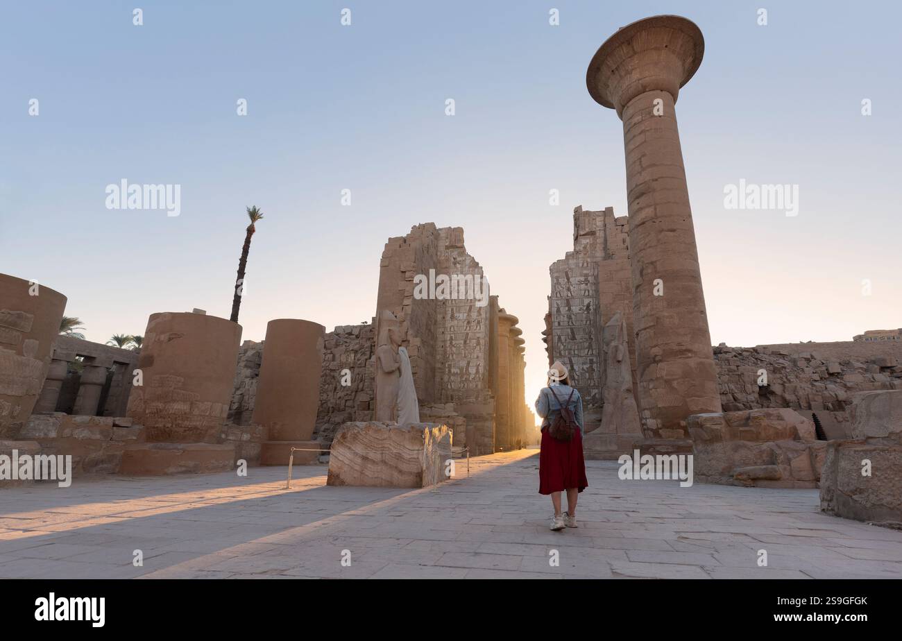 Il viaggiatore felice di donna esplora le rovine dell'antico tempio di Karnak nella città patrimonio di Luxor in Egitto. Gigantesca fila di colonne con gerogliera scolpita Foto Stock