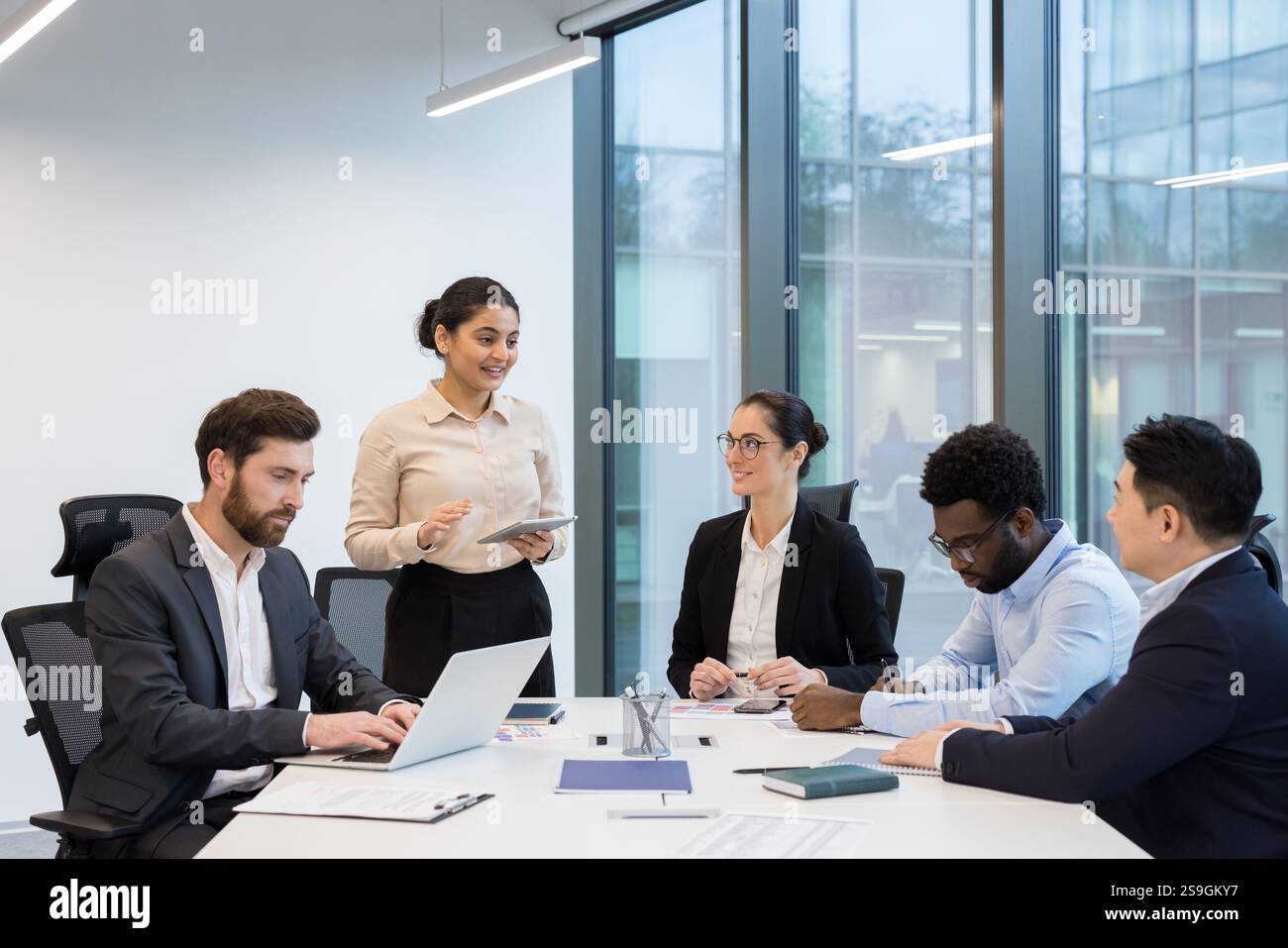 Team aziendale diversificato di successo, gruppo di persone donne d'affari e uomini d'affari che parlano e collaborano, dipendenti soddisfatti e sorridenti all'interno dell'ufficio, al tavolo delle conferenze. Foto Stock