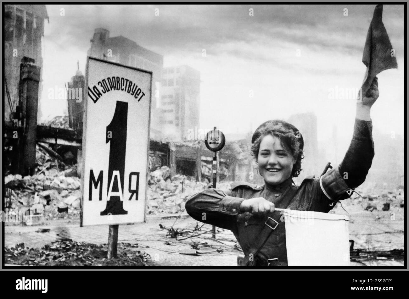 BERLIN RUSSIAN OCCUPAION 1945 Maria Timofeevna Shalneva (Nenakhova), nata nel 1923, caporale del 87° battaglione di manutenzione stradale separato, regola il movimento di equipaggiamenti militari con bandiere, vicino al polveroso frantumato Reichstag di Berlino. Germania Foto Stock