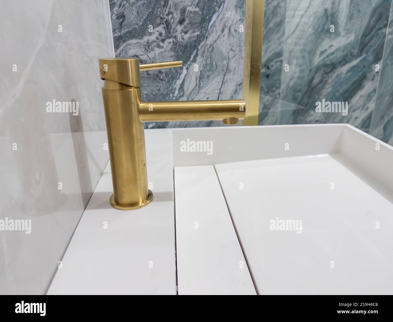 L'elegante rubinetto in ottone si distingue sullo sfondo dell'elegante bagno in marmo Foto Stock