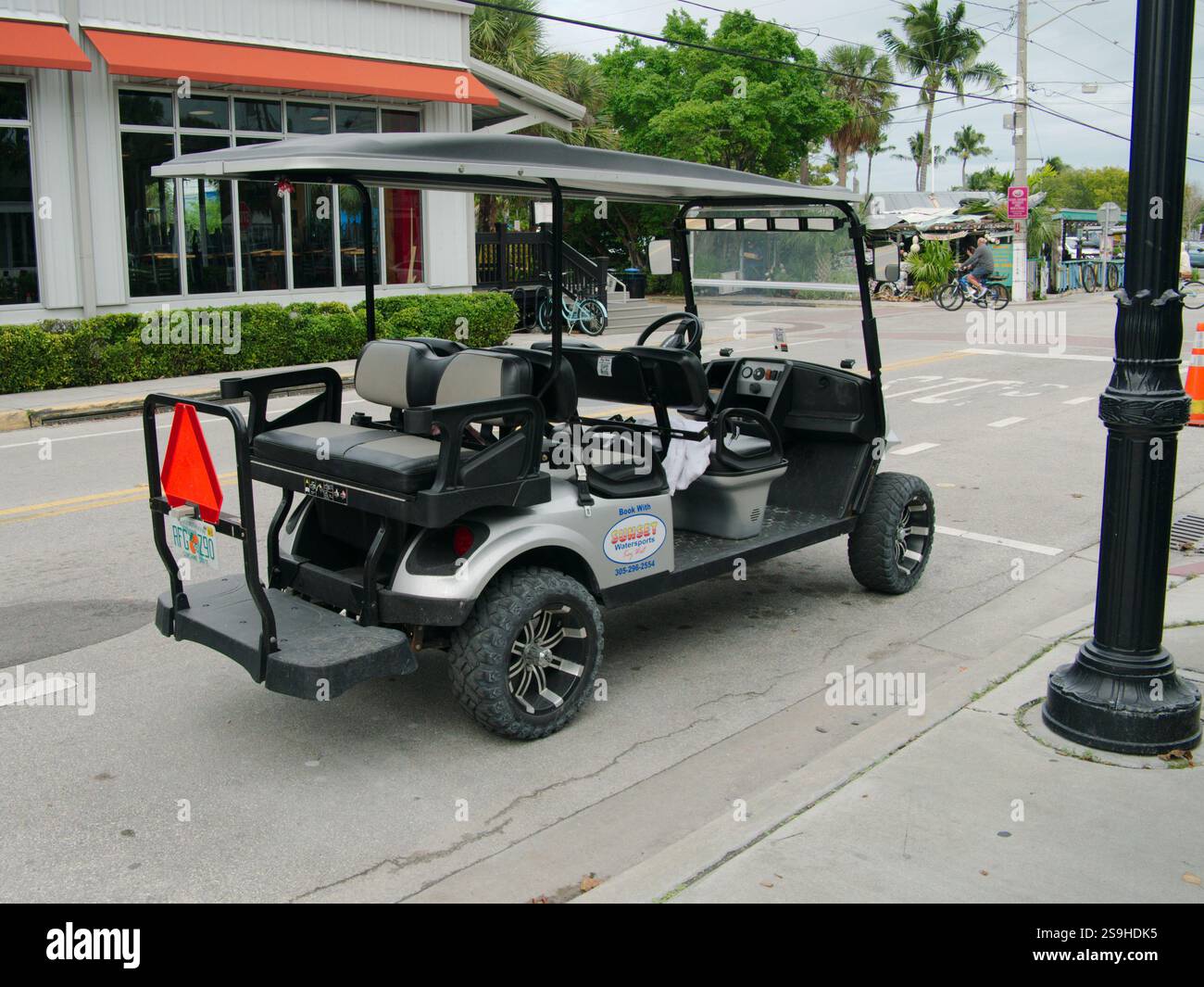 Noleggio di golf cart elettrico per più passeggeri vuoto sulla strada. Edifici e palme sullo sfondo. Solo per uso editoriale 20 gennaio 2025, Key Foto Stock