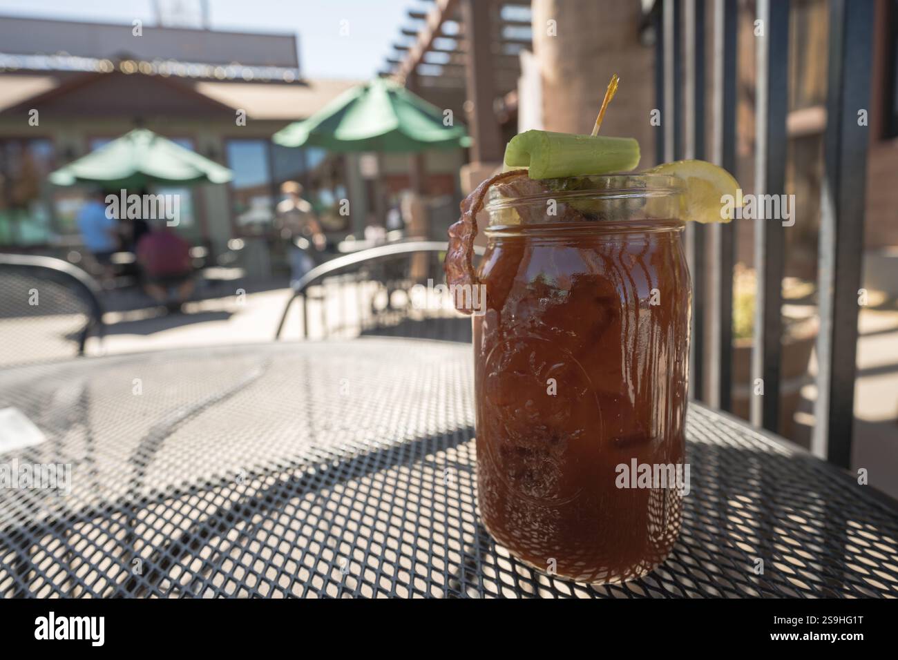 Un cocktail Bloody Mary contenente vodka, succo di pomodoro e spezie servito in un caffè all'aperto a Flagstaff, Arizona. È guarnita con bacon e cele Foto Stock