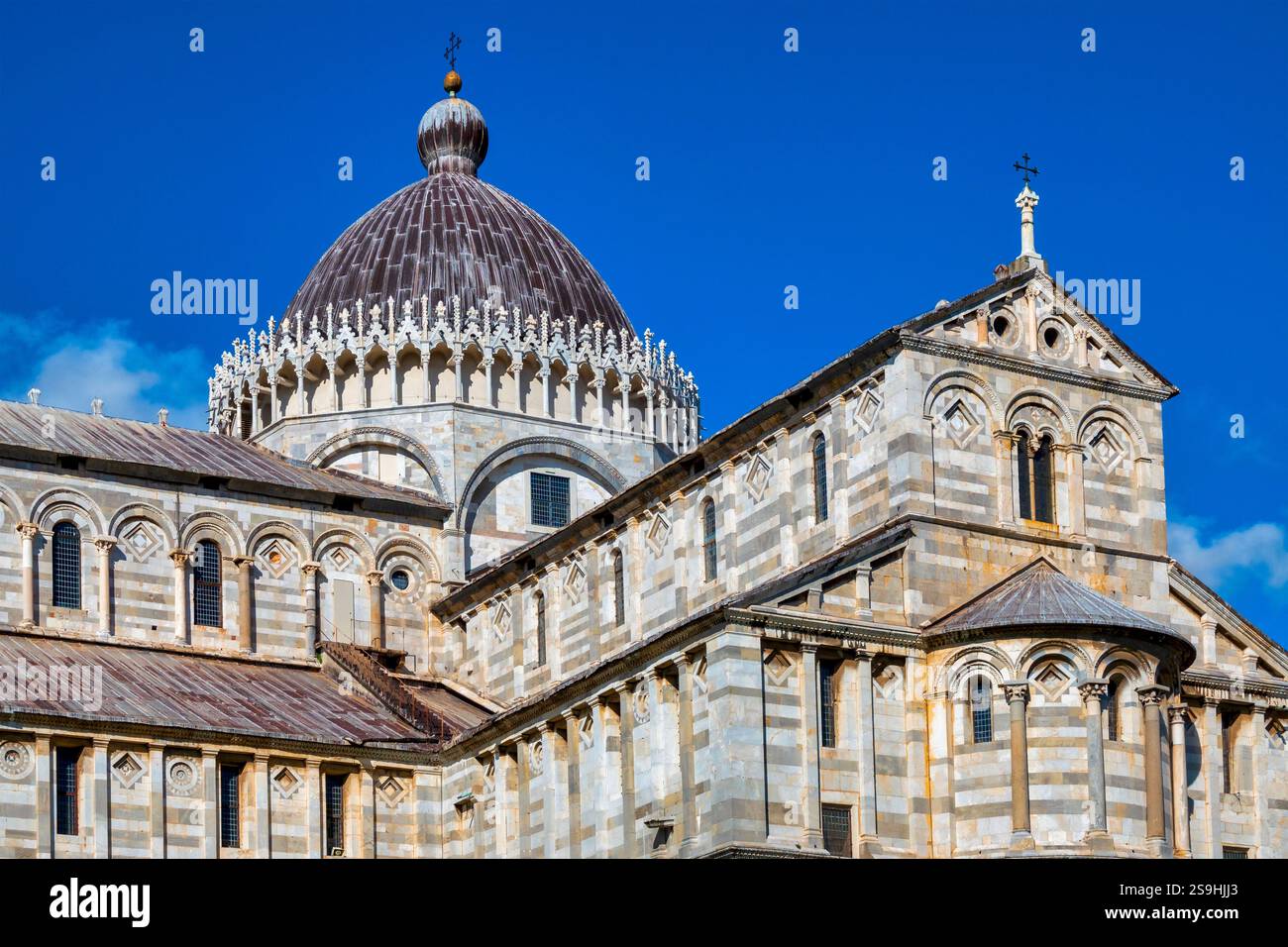 Una vista laterale del Duomo di Pisa in Italia, che mostra la sua architettura romanica con alternanza di marmo bianco e nero Foto Stock