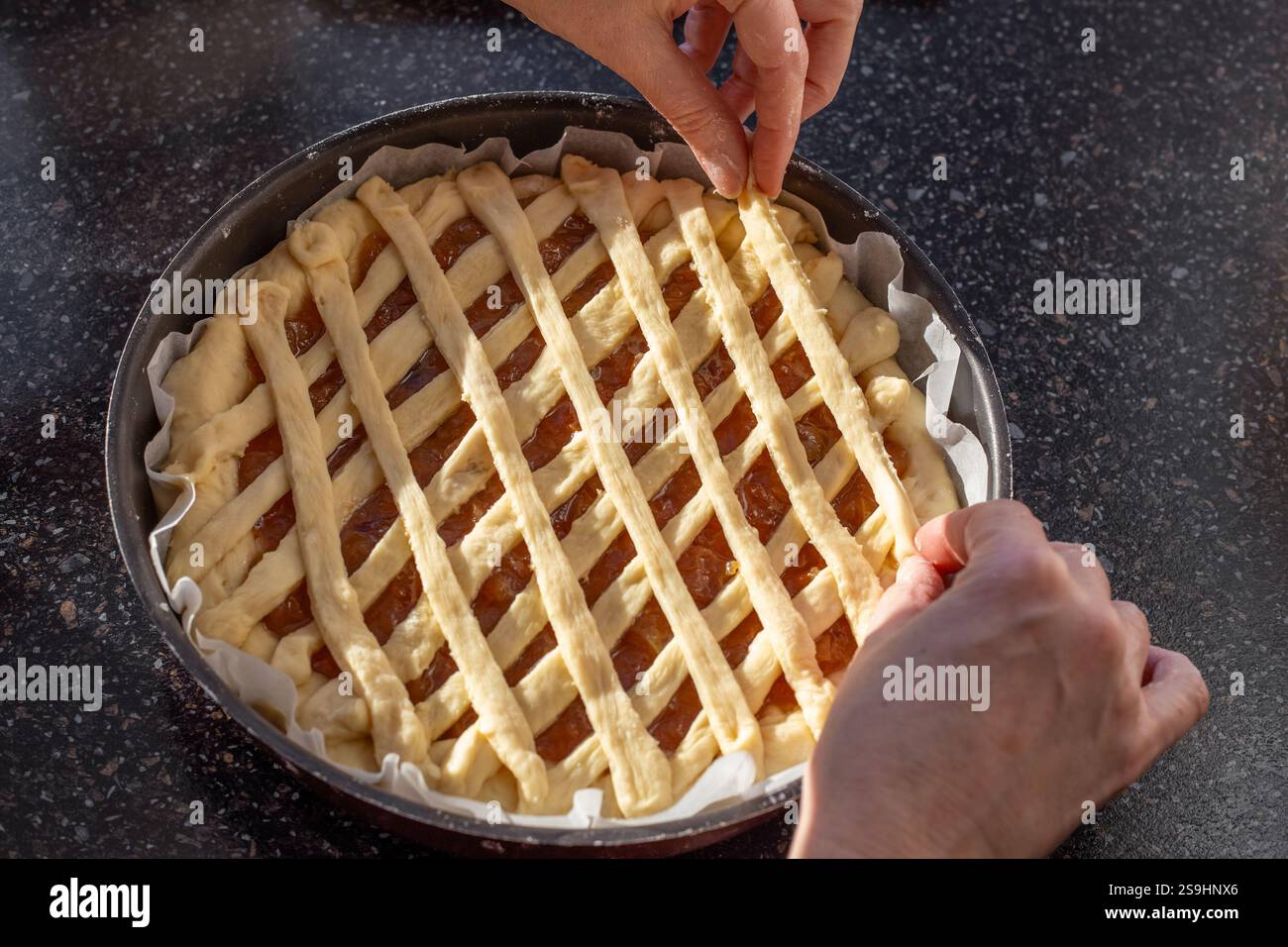 Preparazione di una torta dolce, stendere le strisce di impasto a reticolo sopra il ripieno dolce, visto dall'alto. Foto Stock